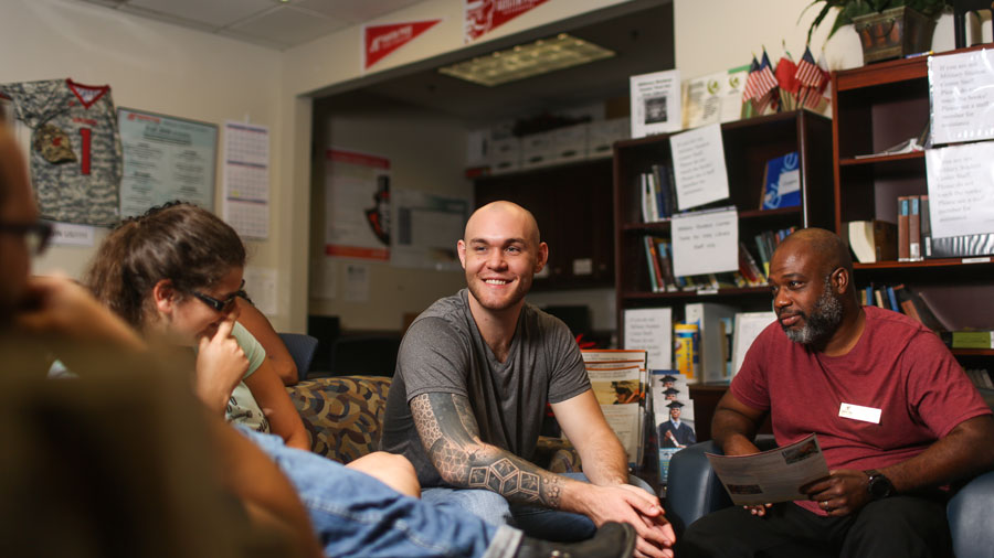 Student standing next to bookshelf in library