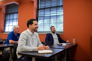 group sitting in a room listening to someone speak