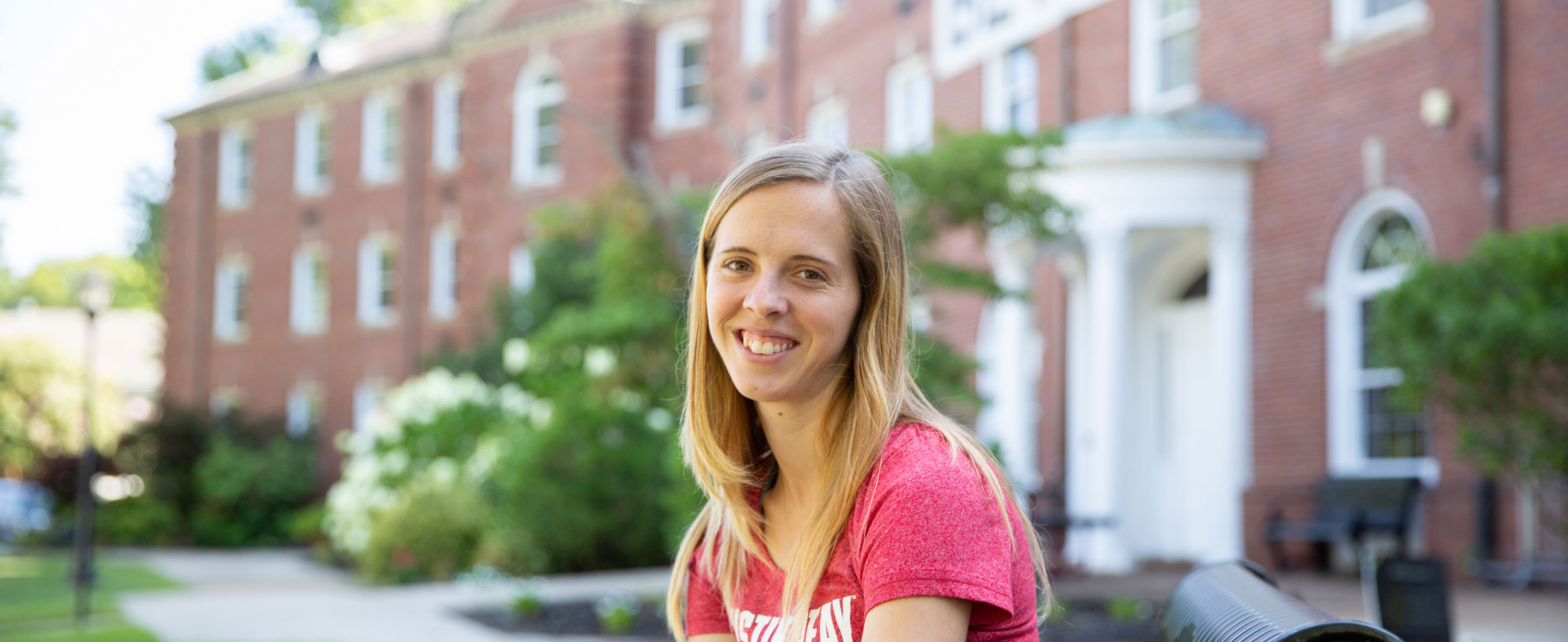 Student sitting on a bench in front of the Ellington Building