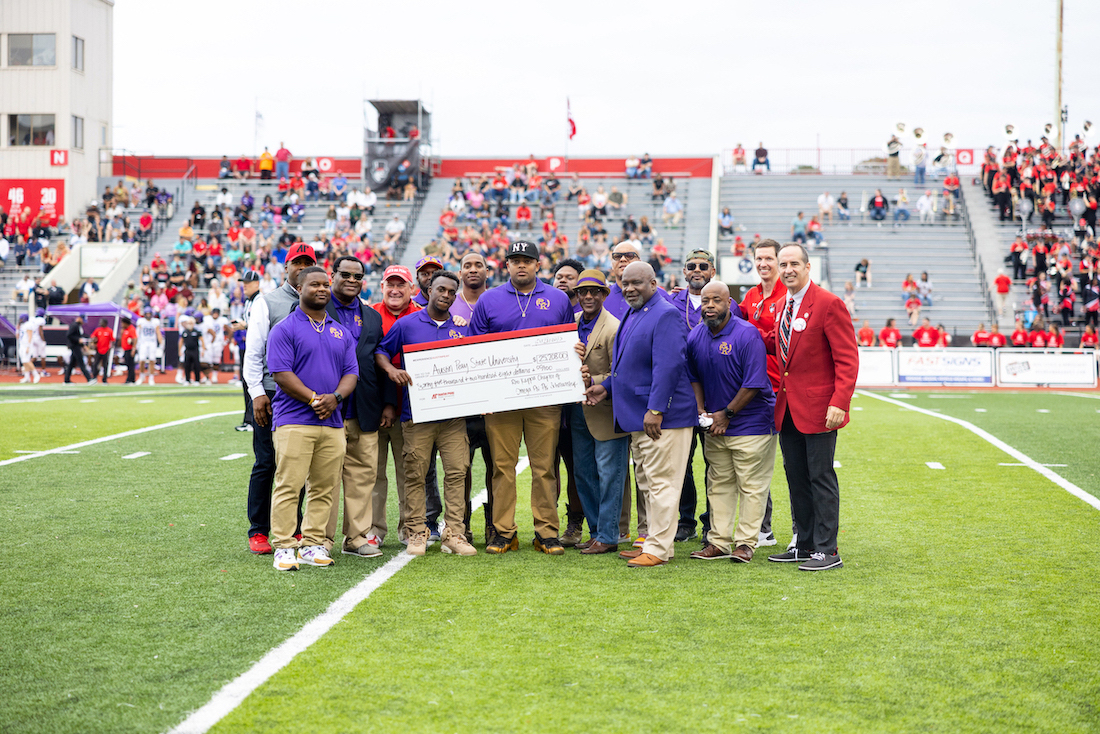 The Rho Kappa Chapter of Omega Psi Phi Alumni Association presents a check to APSU on the field during the Homecoming 2023 football game.