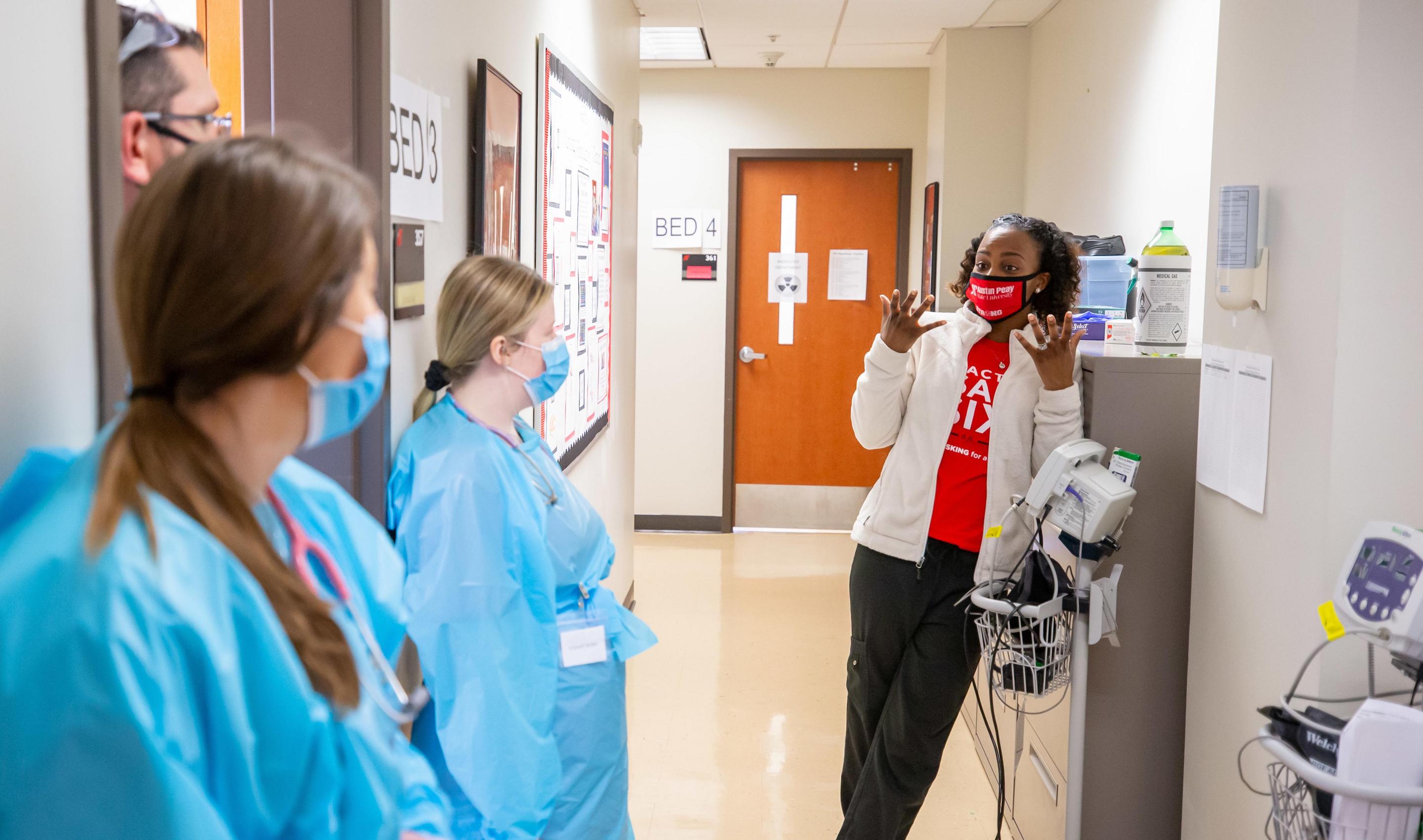 Earlier this month, about 70 Austin Peay State University nursing and radiologic technology students navigated a two-day interdisciplinary simulation where they learned the real-life stakes of collaboration and communication.  The exercise was the first of its kind at Austin Peay, an APSU School of Nursing simulation that brought students from another college – the College of Science, Technology, Engineering and Mathematics – to the school’s simulation lab.  APSU Nursing Simulation Center’s Adrienne Wilk explained the high stakes exercise to the senior-level students before they stepped into the lab.  “Today is for us to improve patient safety and patient outcomes,” she said. “We want you to apply that discipline-specific theoretical knowledge that we’ve lectured to you over the last several months. We want you to apply that knowledge in a real-life clinical setting.”  The objectives of the simulation included understanding the roles each discipline has in a medical setting while collaborating and communicating effectively to improve patient outcomes.  “You have to learn how to communicate,” said Jennifer Thompson, program director for radiography at Austin Peay. “That is one of the biggest takeaways from these scenarios is the students realizing, ‘I had no idea how to talk to the nurses.’  “We need to know how to ask how to help the nurse, and the nurse needs to know how to ask what they can do for you so that you become a healthcare team, not just a rad tech and a nurse,” Thompson added.  Faculty have planned a second interdisciplinary simulation for about 80 junior-level nursing and rad tech students in early April.  Students navigate COVID-19, seizure during simulation  The students separated into teams of two or three nursing students and a rad tech student then rotated among four stations covering two scenarios.  During the March 3-4 exercise, the students cared for a COVID-19 patient and a patient who had fallen and injured her shoulder during a seizure.  Each scenario mimicked real-life settings and included full patient charts and physician orders. Both patients, for example, had doctor’s orders for medical imaging.  In both scenarios, the nursing and rad tech students had to navigate each discipline’s roles while communicating clearly.  The students, for example, had to prepare the COVID-19 patient – played by a high-tech manikin with vital signs – for his diagnostic imaging. The students had to figure out how to position the manikin while keeping him comfortable and the health monitoring equipment secured and working.  A fellow rad tech student volunteered to play the patient in the other scenario and surprised the students with a seizure during medical imaging.  The students gathered with their instructors after each scenario to discuss where they succeeded and where they could improve.  “That’s where all the learning happens,” Wilk said, “especially for visual learners to see the whole patient scenario laid out.”  Thompson agreed: “You don’t realize how much is happening during the simulation until you watch the debriefing.”  ‘We need them to help with the patient’  Nursing senior Daketra Mason’s biggest takeaway centered on communication, especially between disciplines across campus. The School of Nursing is in the College of Behavioral and Health Sciences, and the rad tech program is in CoSTEM’s Department of Allied Health Sciences.  “Throughout the whole sim, I saw how important it is communicating with everybody, with other healthcare workers and the patient,” she said.  Rad tech senior Valerie Picataggio joined Mason and nursing senior Hannah McElroy in the scenario.  “In a real setting, (Valerie) wouldn’t have known what we knew about the patient so we would have had to explain to her what was happening,” Mason said.  The COVID-19 patient in the simulation, for example, had a pressure sore that restricted his movement.  “And from my perspective, I’m used to getting in and getting out, but I could put that patient’s safety at risk because I didn’t know about his pressure sore,” Picataggio said. “For the most part, we stay out of the nurses’ way, get the image and then leave.”  McElroy said the simulation allowed her to recognize the need to collaborate.  “We do work pretty closely with (rad tech),” she said. “They don’t need to stay out of the way, they’re not in the way, we need them to help with the patient as well.”  Picataggio also noted the importance of including a COVID-19 patient in the scenario.  “You don’t treat COVID patients differently just because they’re vented,” she said. “As long as we’re protecting ourselves and being smart, they shouldn’t feel any kind of aversion to them.  “That could be my family member lying there.”  To learn more  • For more about the Department of Allied Health Sciences, visit www.apsu.edu/allied-health/. • For more about the School of Nursing, go to www.apsu.edu/nursing/.