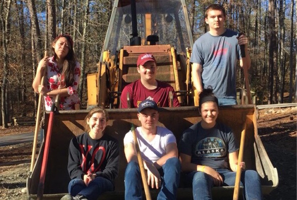 Students sit on a backhoe's bucket during an alternative break trip.