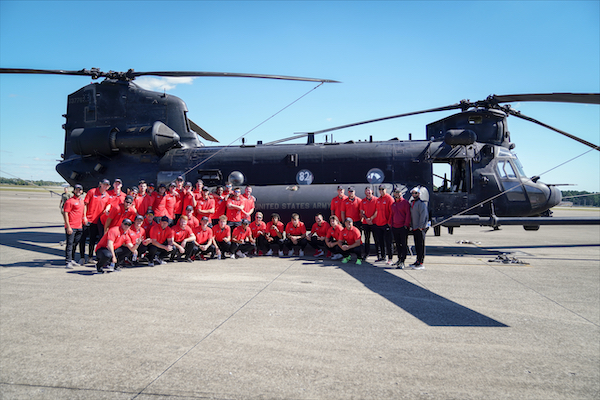 The APSU Baseball team stands in front of a 160th Helicopter