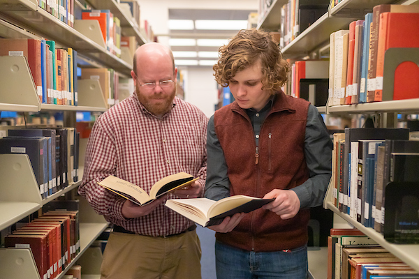 Dr. Kevin Harris and Nick Foreman look through books at the library.