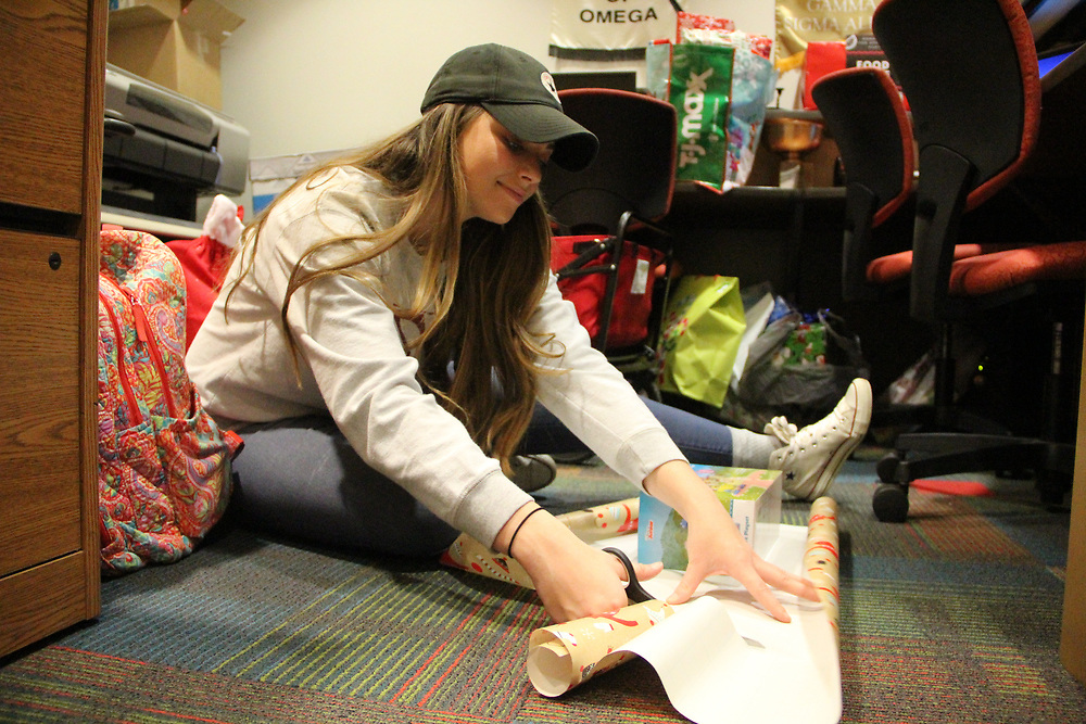 Anna Kail, former student employee in the office of Student Affairs, helps wrap gifts for the Help an Elf program in December 2018. 
