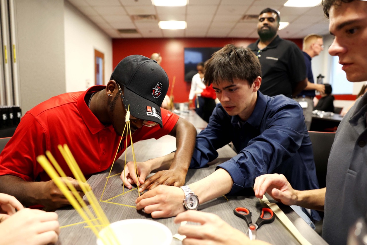 Joshua Martin, left, teams up with Issac Billeter, center, and Andrew Schramkowski on an engineering puzzle during the program.