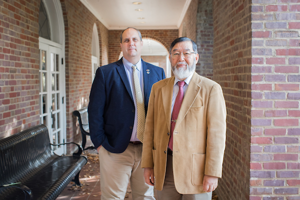 Dr. David Rands and Mr. Yoshio Koyama stand near the entrance to Harned Hall.