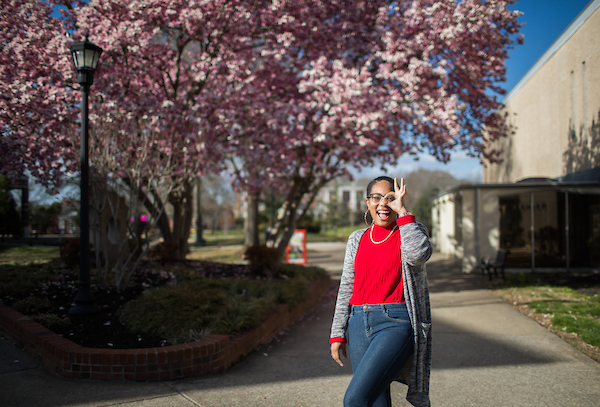 Celeste Malone mimics a monocle with her fingers around her eye.