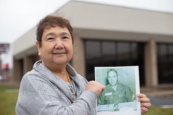 Wilma Newton holds a photo of her father in front of the upcoming military family student center.