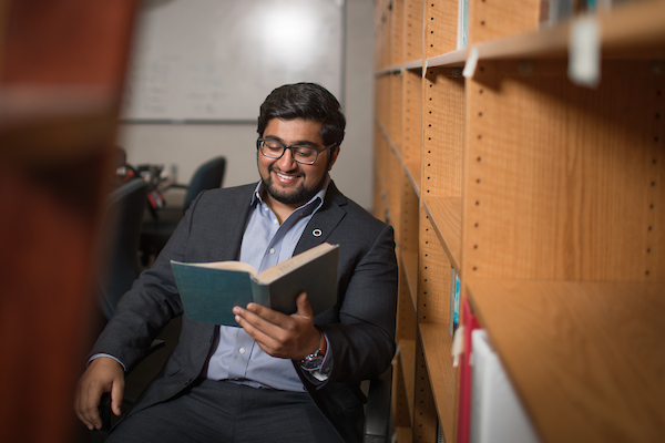 Former PPH student Waqas Ahmed reads a book in a library.