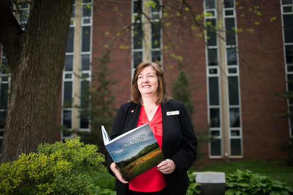 Dr. Cheryl Lambert browses through a book while standing in front of the APSU Claxton Building.