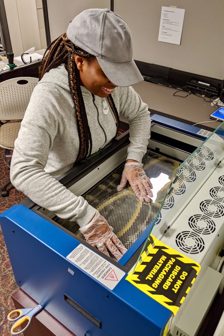 Ciara Grandberry places plastic for face shields into a laser printer at the APSU GIS Center.