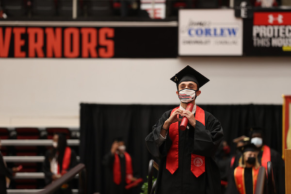 A student walks across the stage during commencement.