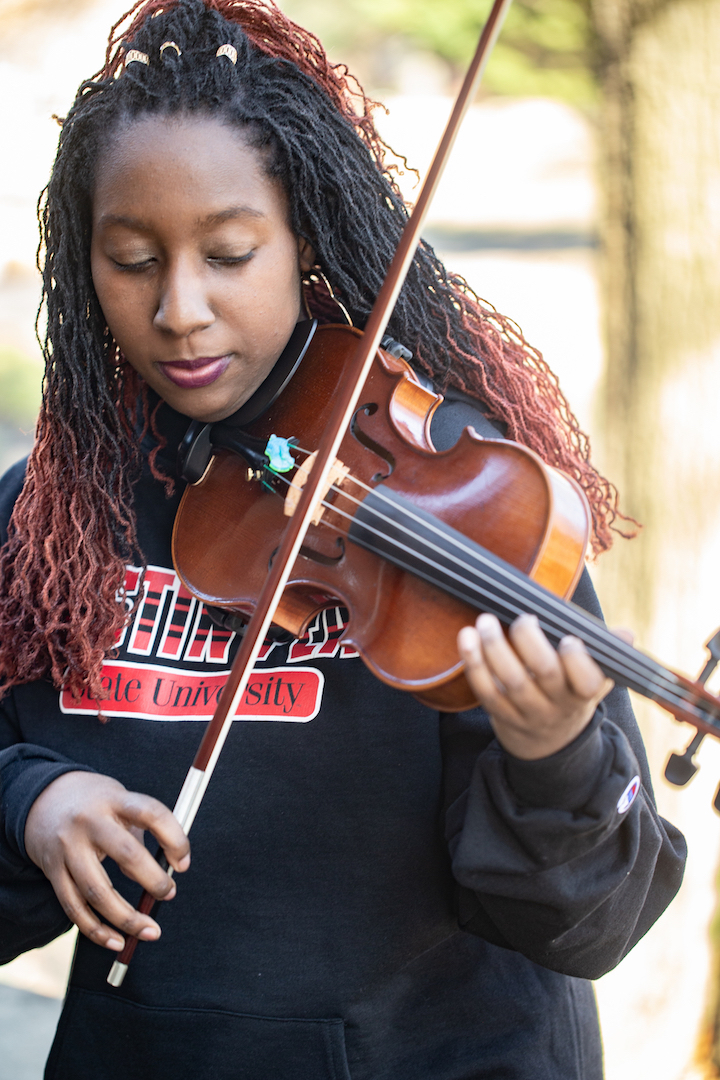 Zoe Johnson’s love for music has shaped both her life and her time at Austin Peay. “I grew up in a musical family. My mom was a piano teacher, my dad was in a band in college and my brother is a Christian rapper,” she said. “I came to love the violin in the sixth grade.” Last December, Johnson’s love for music helped bring hope to a world suffering from a growing pandemic. At her hometown Kroger in Memphis, she played Christmas music between her shifts to spread holiday cheer. Her playing became popular, and Fox 13 picked up the story. “People were very generous with their donations and encouraging words,” she said. “My whole thing was just to spread Christmas cheer, and I really hope people got that.” Johnson loves playing her violin for others, and she even started her own gig service this past fall. “Coming here to college has definitely helped me build a bigger platform for playing the violin,” she said. She has played in a couple of weddings and a funeral. Not only does Johnson play in-person gigs, but she also uses her social media channels to her advantage. With the ongoing COVID-19 pandemic, live performances have been limited. Many of her fans know her through her social media accounts, “@avidviolin.” “I kind of just came up with it, and I’ve actually had it since my senior year of high school,” she said. “I wanted something very original for me, and I just stuck by it and now I’m glad I did.” ‘Why not keep doing it every week’ Johnson was not big on social media before. “It was kind of dormant for me,” she said. “One day my brother brought it to my attention that Kent Jones, a gospel artist I love, had a challenge on Instagram where you did a cover of your favorite song and if he likes it, he’ll repost it.” Kent Jones reposted Johnson’s cover, which gave her inspiration to further her musical career. “I thought, ‘Hey, if I could get this sort of attention, why not keep doing it every week,’” she said. Johnson has had various artists repost her work and given her encouraging words. Not only does Johnson host IGTV or Facebook Live videos, but she also posts videos of her playing with a green screen. “I definitely think the green screen works because it gives people something to focus on and also sort of imagine it in a world,” she said. “I definitely want people to enjoy the music more than anything. I want them to just be encouraged and enjoy the music as it uplifts them.” ‘Push for bigger and better things’ Johnson had her eyes set on Austin Peay when applying to colleges. “Austin Peay has this really awesome festival they do for high schoolers, and I went all four years, so it was a very obvious choice,” she said. “Everyone is kind and encouraging to each other, and it’s kind of like a working together experience when it comes to all the instrumentalists and vocalists.” “Austin Peay has helped push me to be better and push for bigger and better things. Austin Peay has a great music department for that,” she said. “I plan on being a teacher for violin one of these days. I’m also trying to make a job out of it definitely.” To learn more For more about Austin Peay’s Department of Music, visit www.apsu.edu/music/.