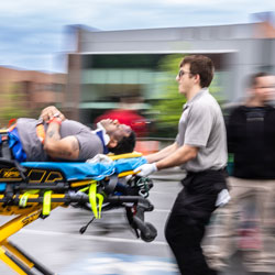 Student rushing a simulation participant to the ambulance on a stretcher.