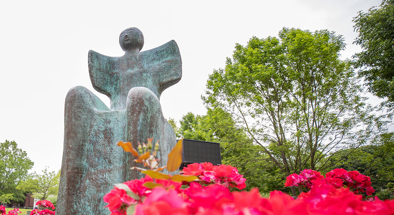 Green Man Statue and flowers outside the University Center.
