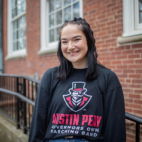 Austin Peay education student stands in front of a building. 