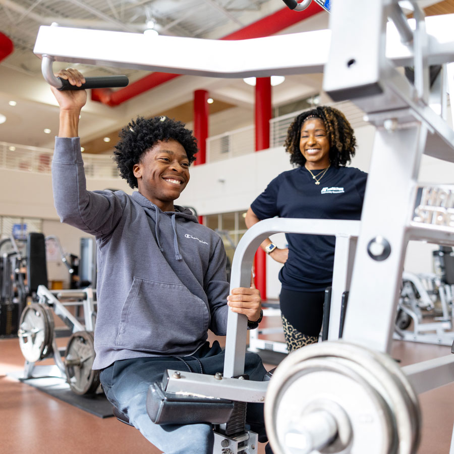Student being coached on how to use the gym equipment