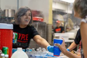 A staff member hands a prepared drink to another person.