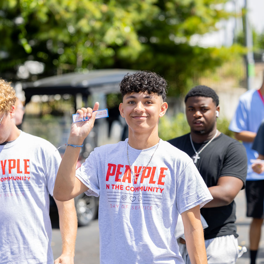 Group of students in their peayple in the community day tshirts walking through a parking lot