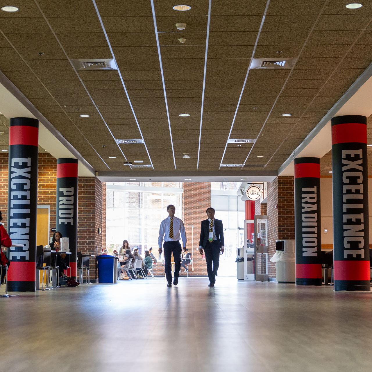 Two people walking between the pillars in the University Center