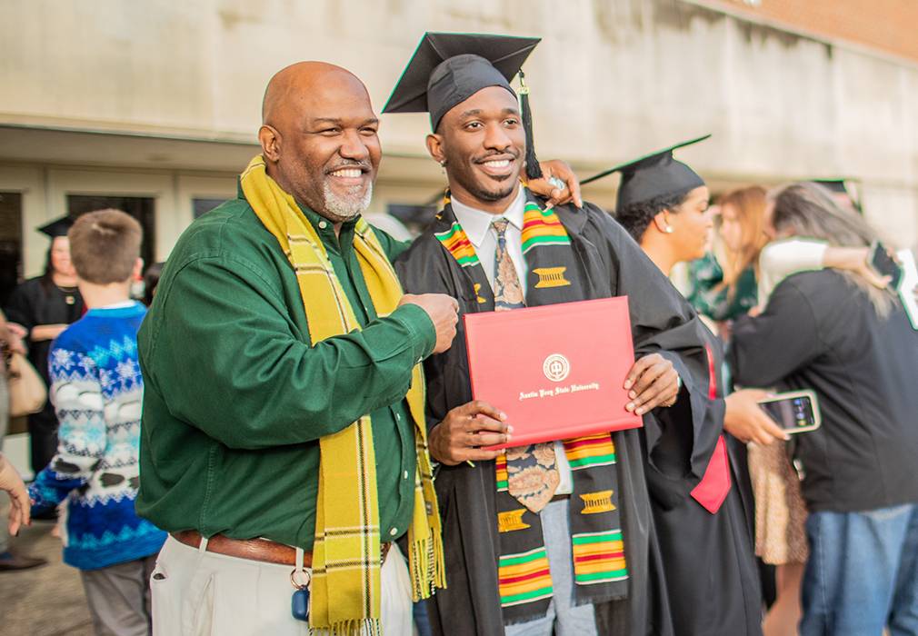 Student posing for photo with family at commencement
