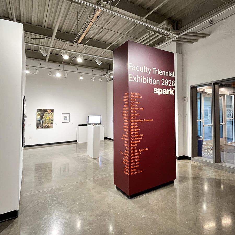 Signage for "Faculty Triennial Exhibition 2026: Spark" on a maroon column, displaying names of participating faculty artists, set in a modern art gallery.