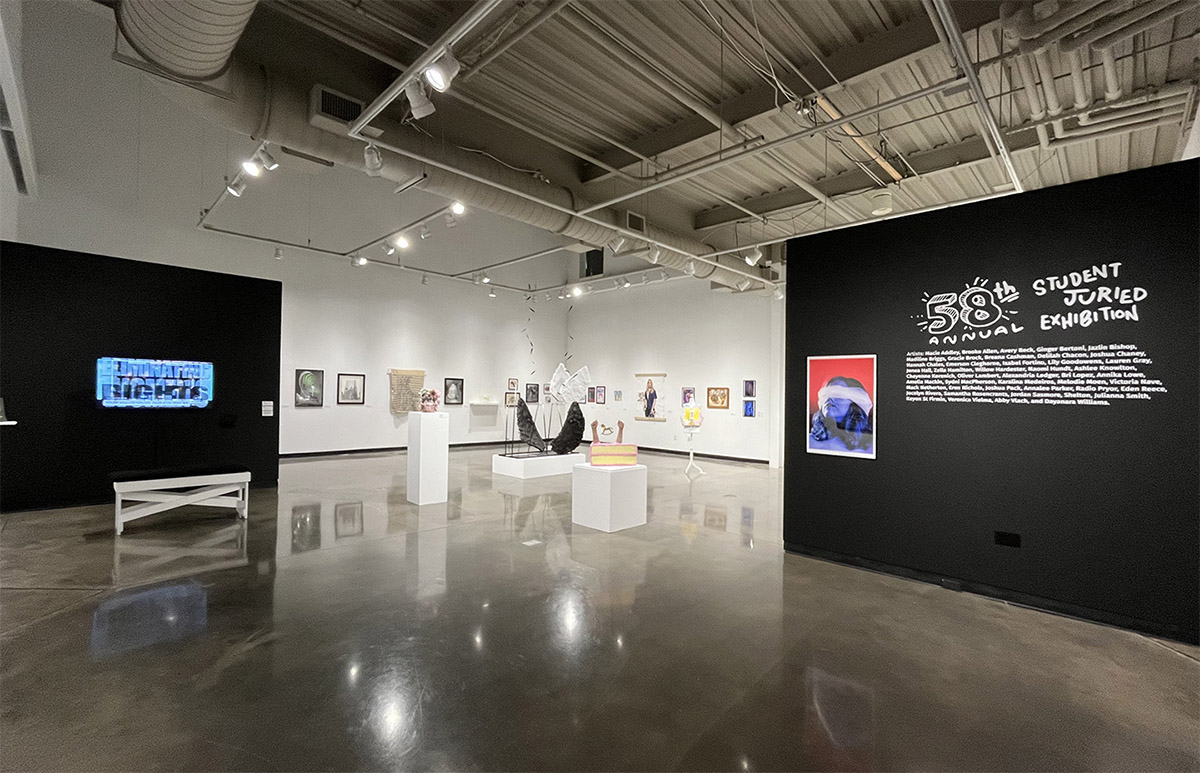 Art gallery interior with sculptures and framed artworks on display.