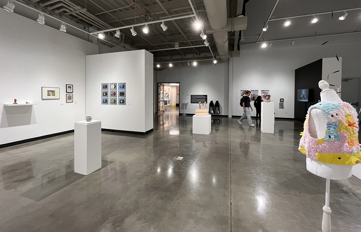 Art gallery with various artworks, sculptures, and a mannequin wearing a colorful vest.