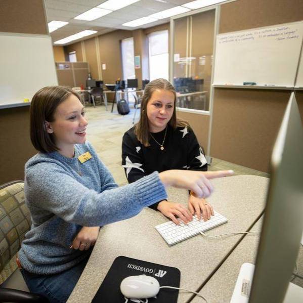 A staff member of the APSU Writing Center assisting a student on the computer.