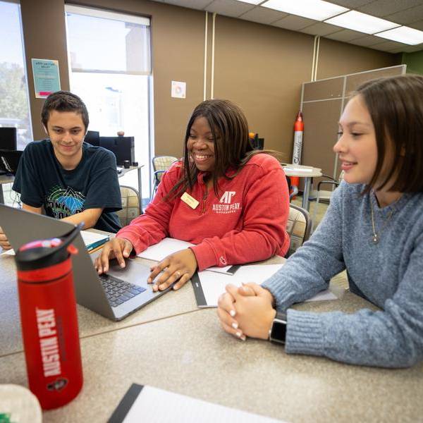 Students and staff of the APSU Writing Center sitting around a laptop.